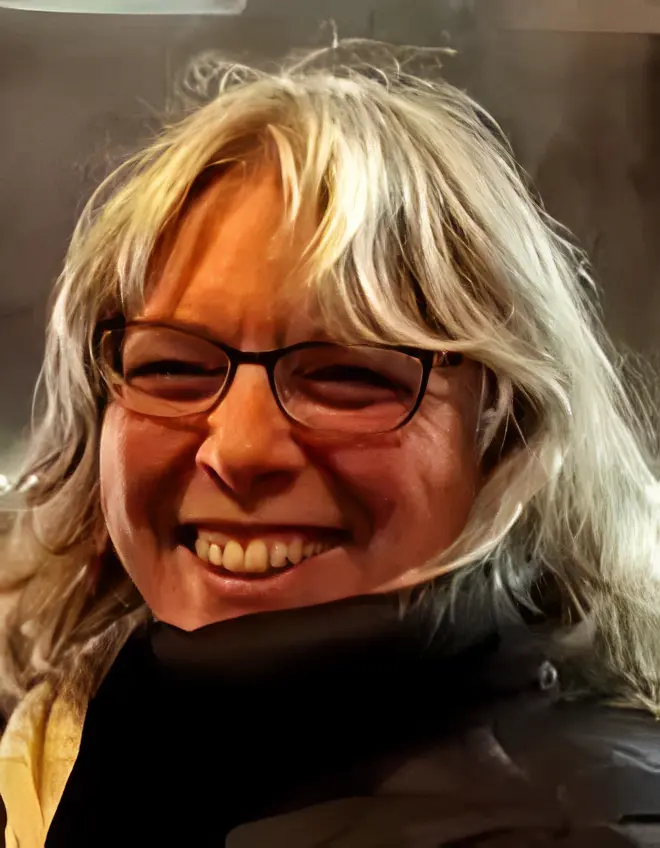 Cheerful person with long hair and glasses.