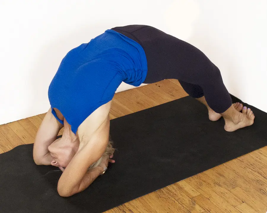 Person practicing yoga backbend on mat.