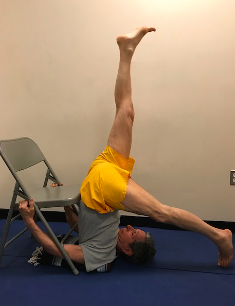Man doing yoga pose with chair support