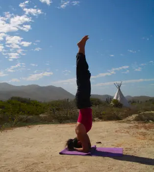 Headstand pose near teepee and mountains