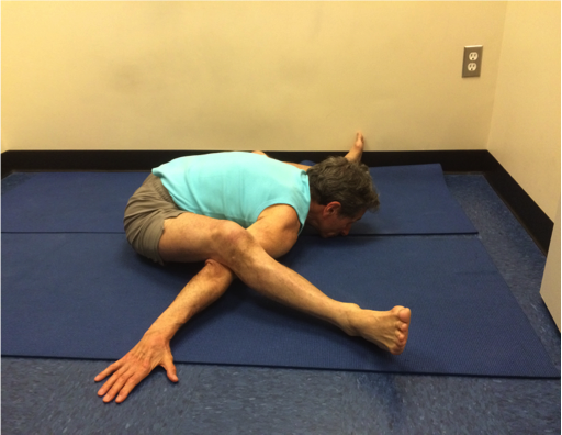 Person practicing advanced yoga pose on mat.