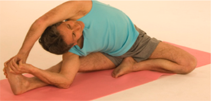Individual in blue shirt stretching on mat