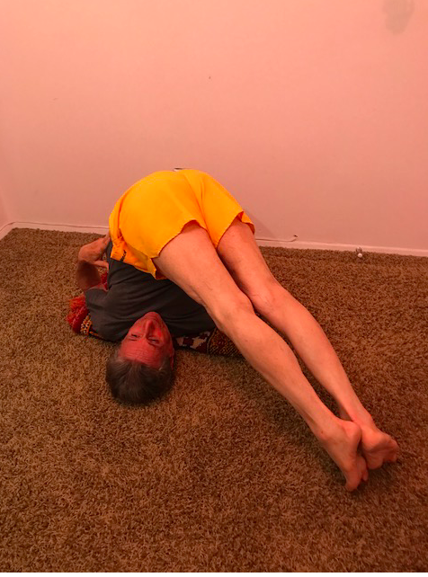 Person in yoga plow pose indoors