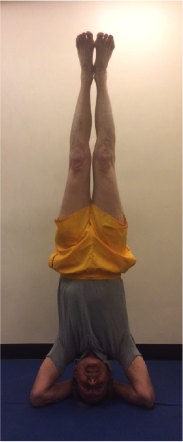 Individual doing a headstand on blue mat.