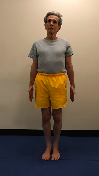 Man standing in yellow shorts indoors.