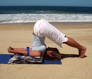 Woman in plow pose on beach
