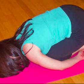 Woman in yoga pose on wooden floor.