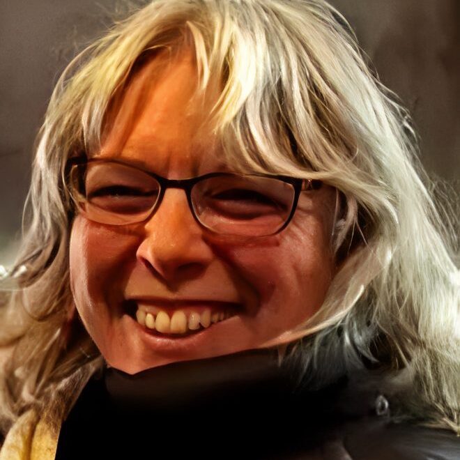 Cheerful person with long hair and glasses.