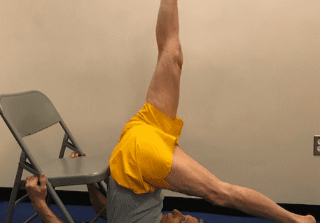 Man doing yoga pose with chair support
