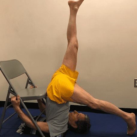 Man doing yoga pose with chair support