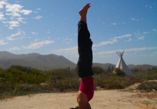 Headstand pose near teepee and mountains