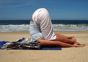 Person practicing yoga on a sandy beach