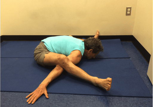 Person practicing advanced yoga pose on mat.