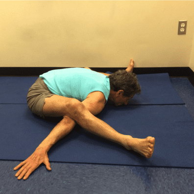 Person practicing advanced yoga pose on mat.