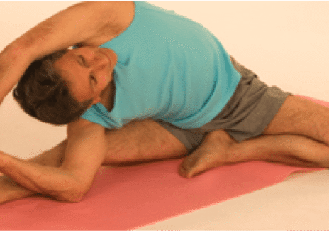 Individual in blue shirt stretching on mat