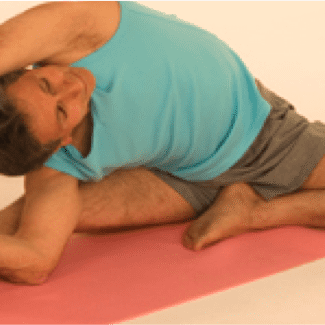 Individual in blue shirt stretching on mat