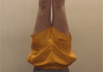 Individual doing a headstand on blue mat.
