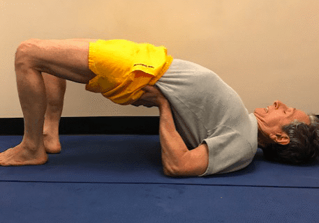 Man practicing bridge pose on mat