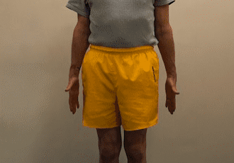 Man standing in yellow shorts indoors.