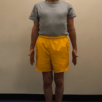 Man standing in yellow shorts indoors.